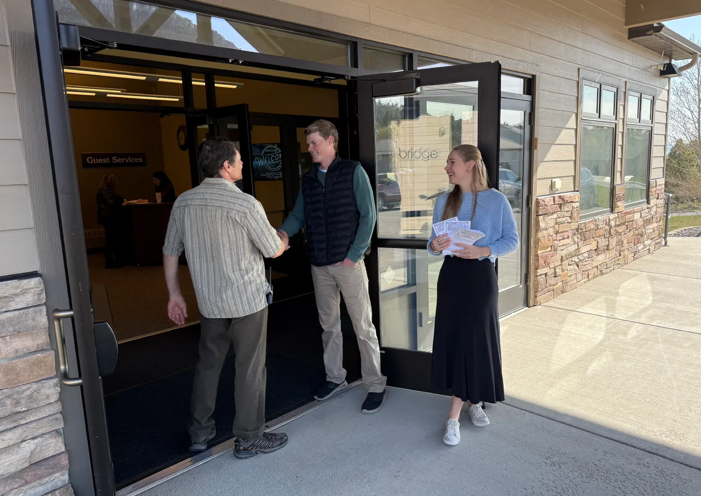 A guest being welcomed at the open entrance of Bridge Helena in Helena, Montana.