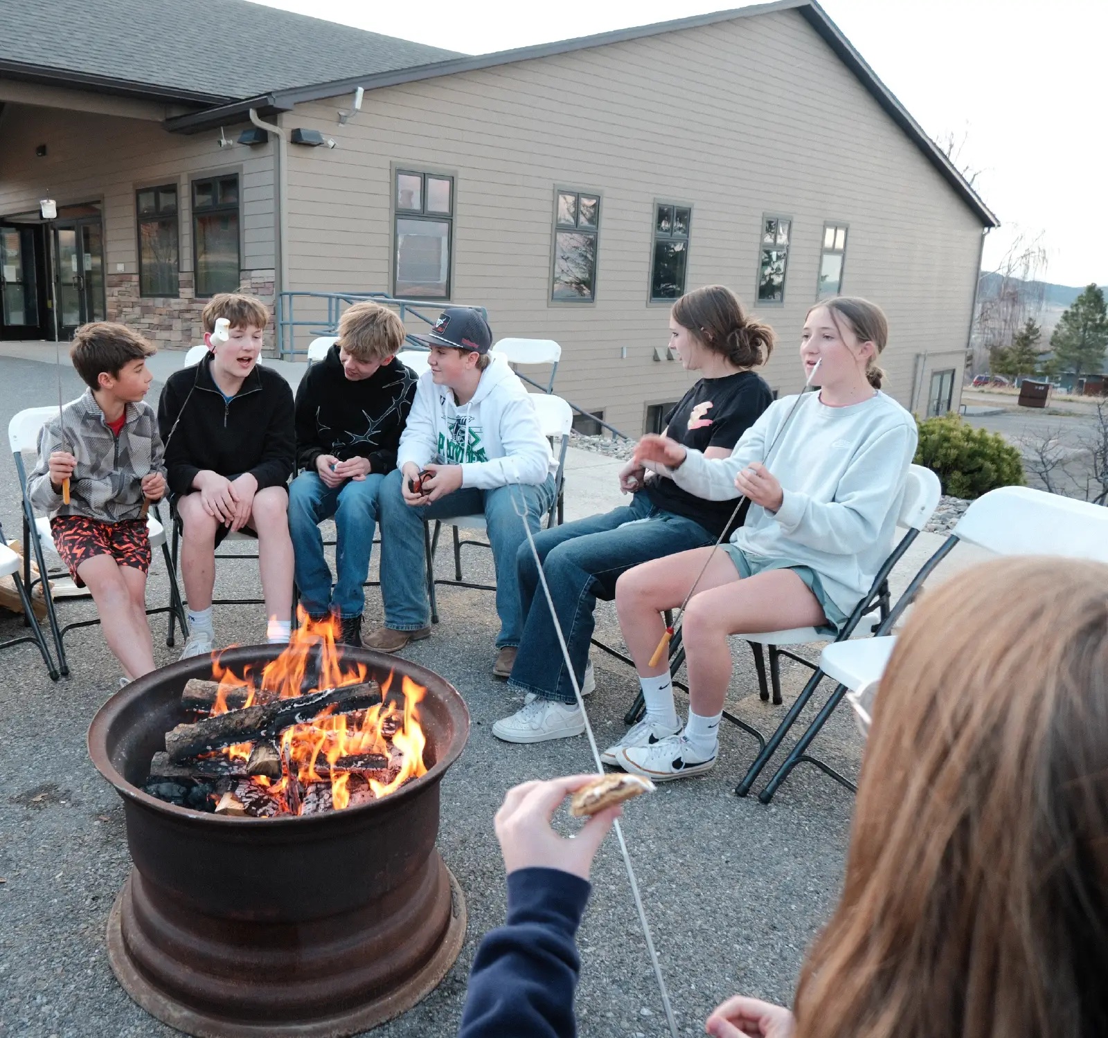 Refuge Youth students roasting marshmallows around a campfire at Bridge Helena in Helena, Montana